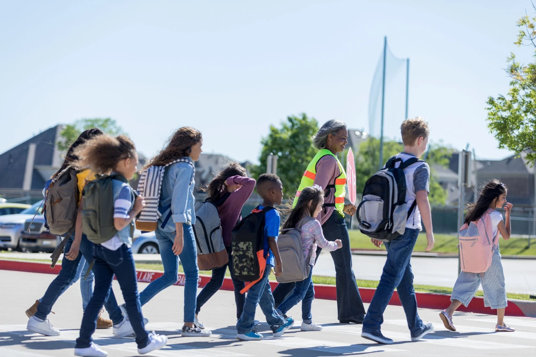 Image of students walking across a crosswalk with a crossing guard.